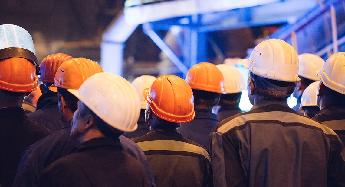 Image of a group of men in hard hats from behind.